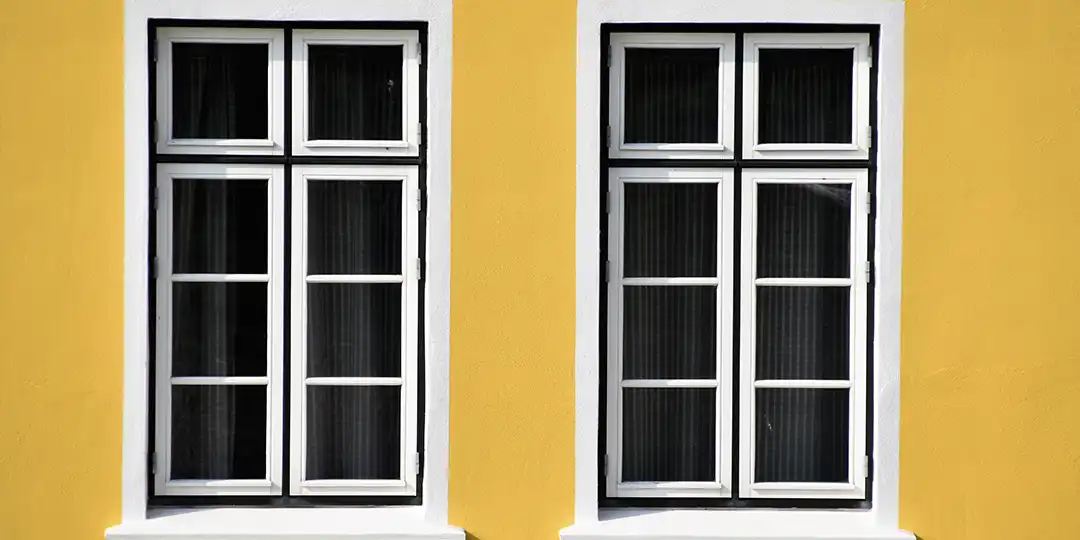 Deux fenêtres propres sur un mur jaune.